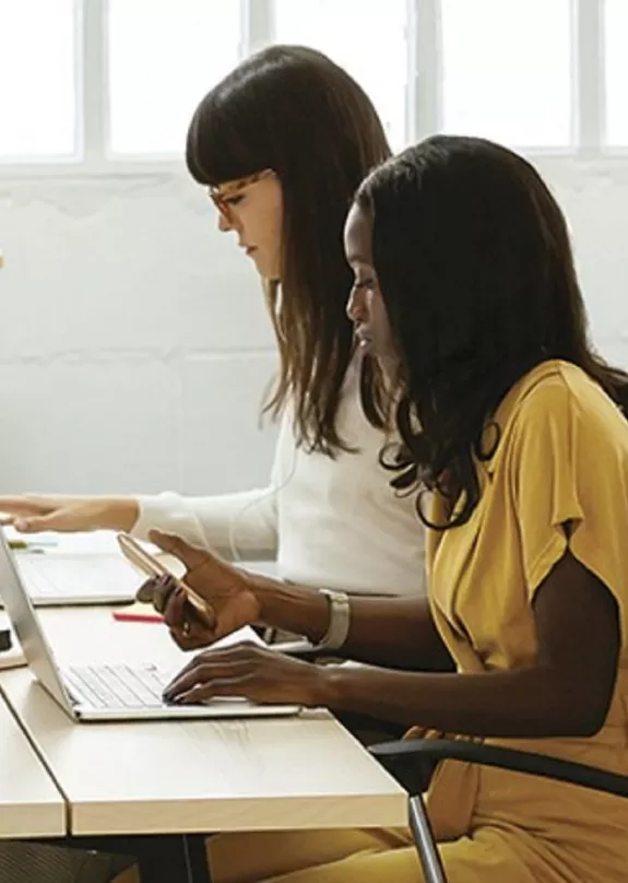 Three workers at communal desk with a printer in the background