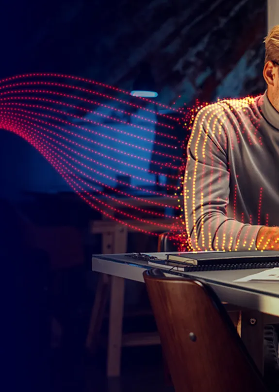 Two people sat at a table looking at a laptop, with pulse graphic connecting the people with the technology